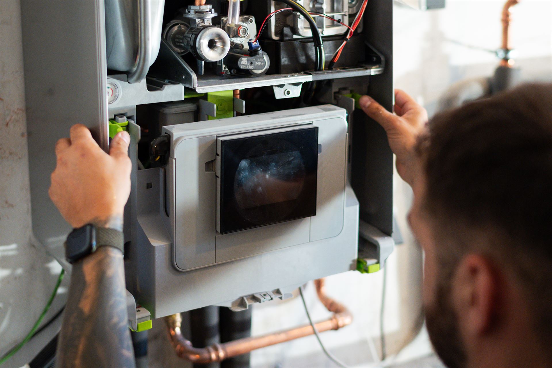 Techniker nimmt die Verkleidung eines wandhängenden Heizgerätes ab, die Technik im Inneren ist sichtbar